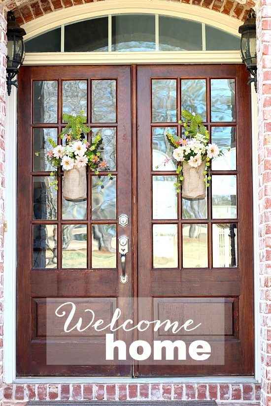 Welcome home with flowers in burlap containers.